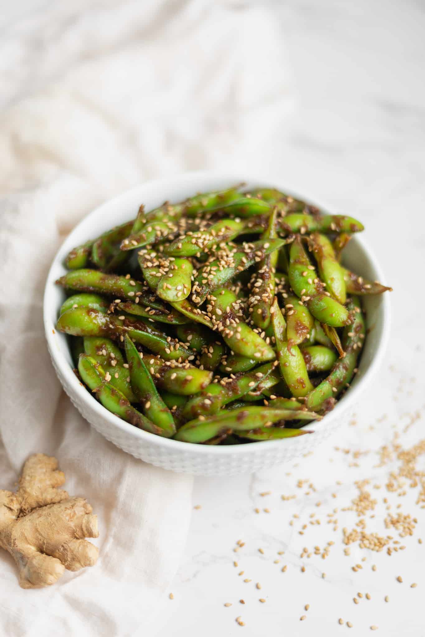 edamame in a white bowl topped with sesame seeds