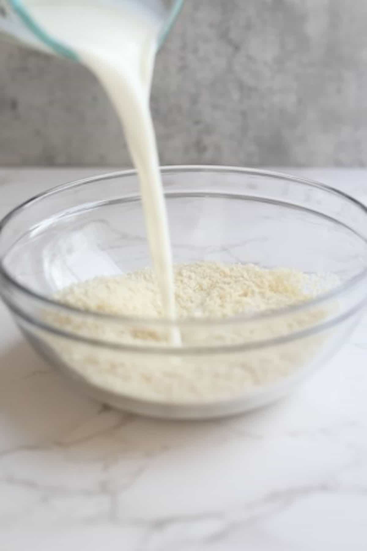 buttermilk being poured into a glass bowl with breadcrumbs
