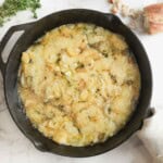 Caramelized Onion and Gruyere Cheese Dip in a black cast iron skillet next to fresh thyme and bread.
