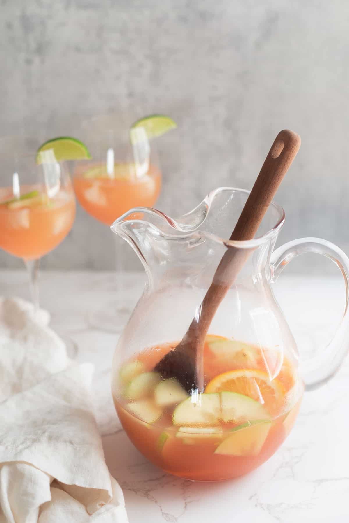 clear pitcher of sangria with a wooden spoon sticking out