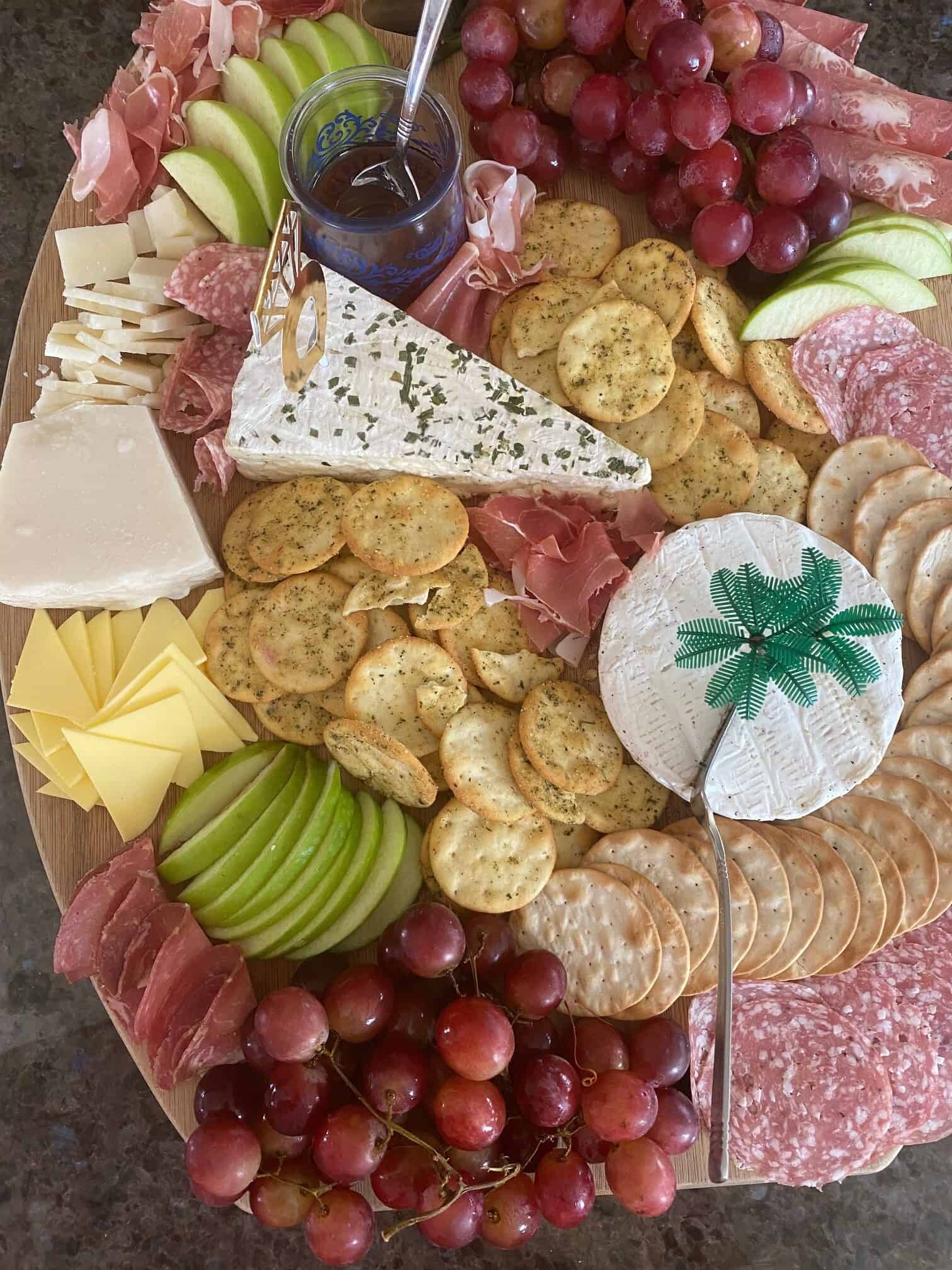 circular charcuterie board with crackers, cheeses, fruit, and meats