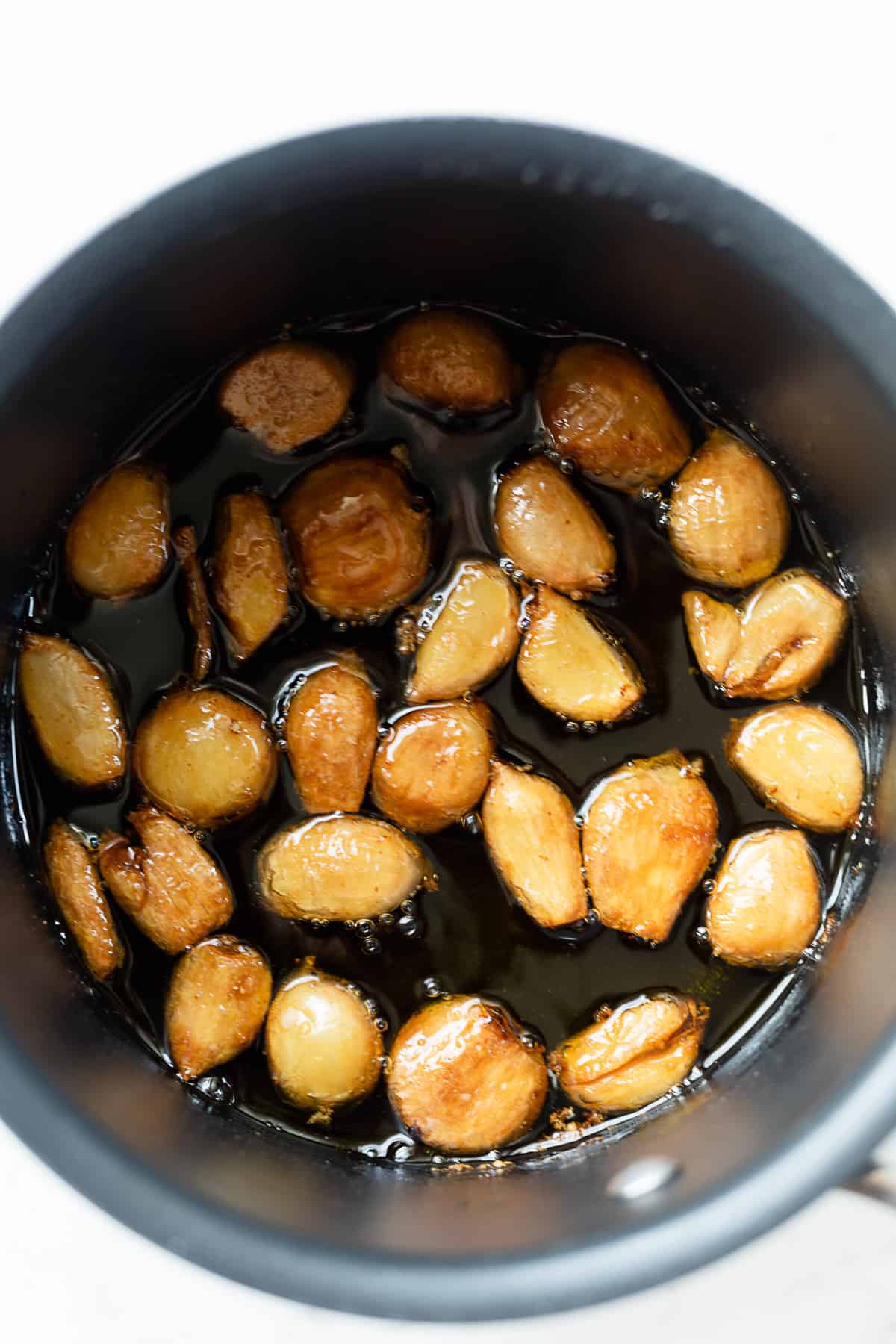 cooked garlic confit in a pot of oil