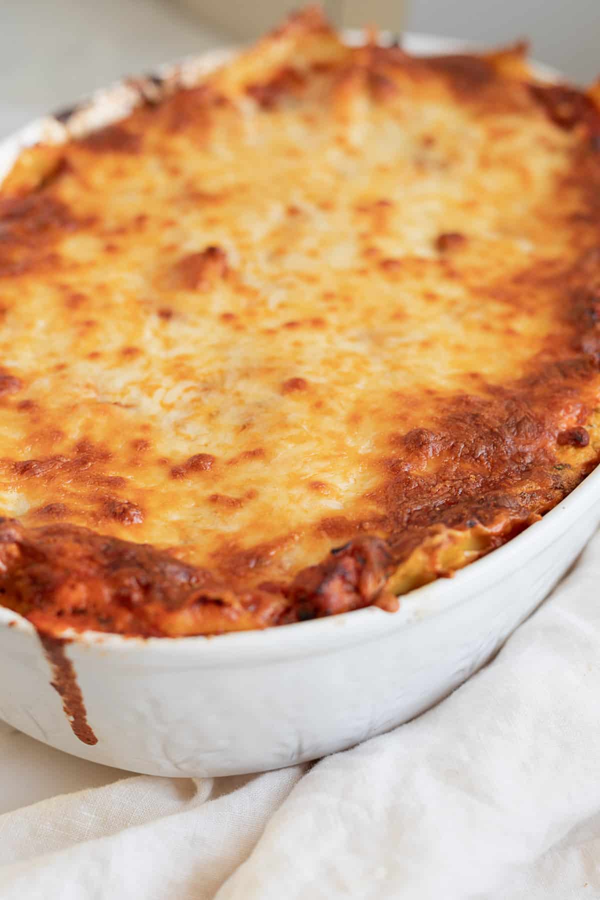 lasagna in a white casserole dish with a cheesy top
