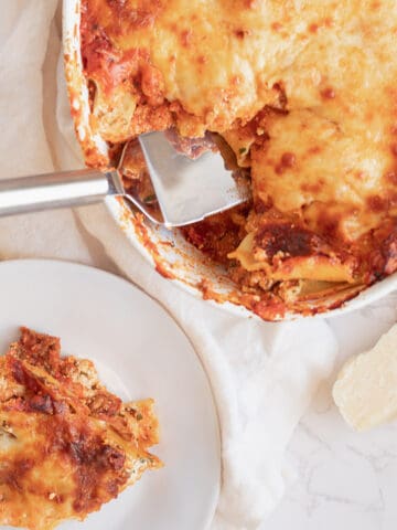 lasagna al forno being served onto a white plate