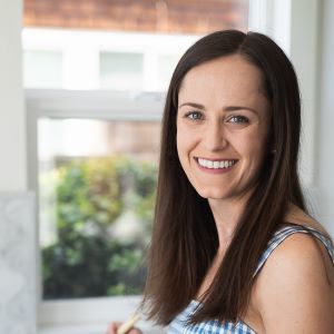 Photo of Caitlin with brown hair smiling and cooking