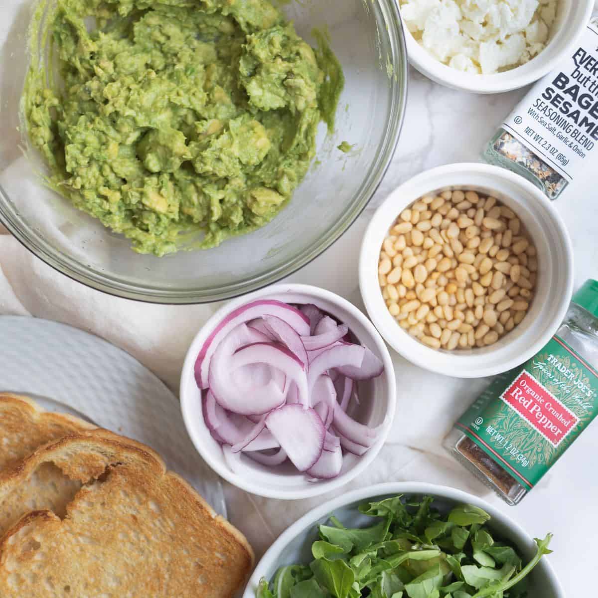 smashed avocado in a bowl, toast, and topping suggestions