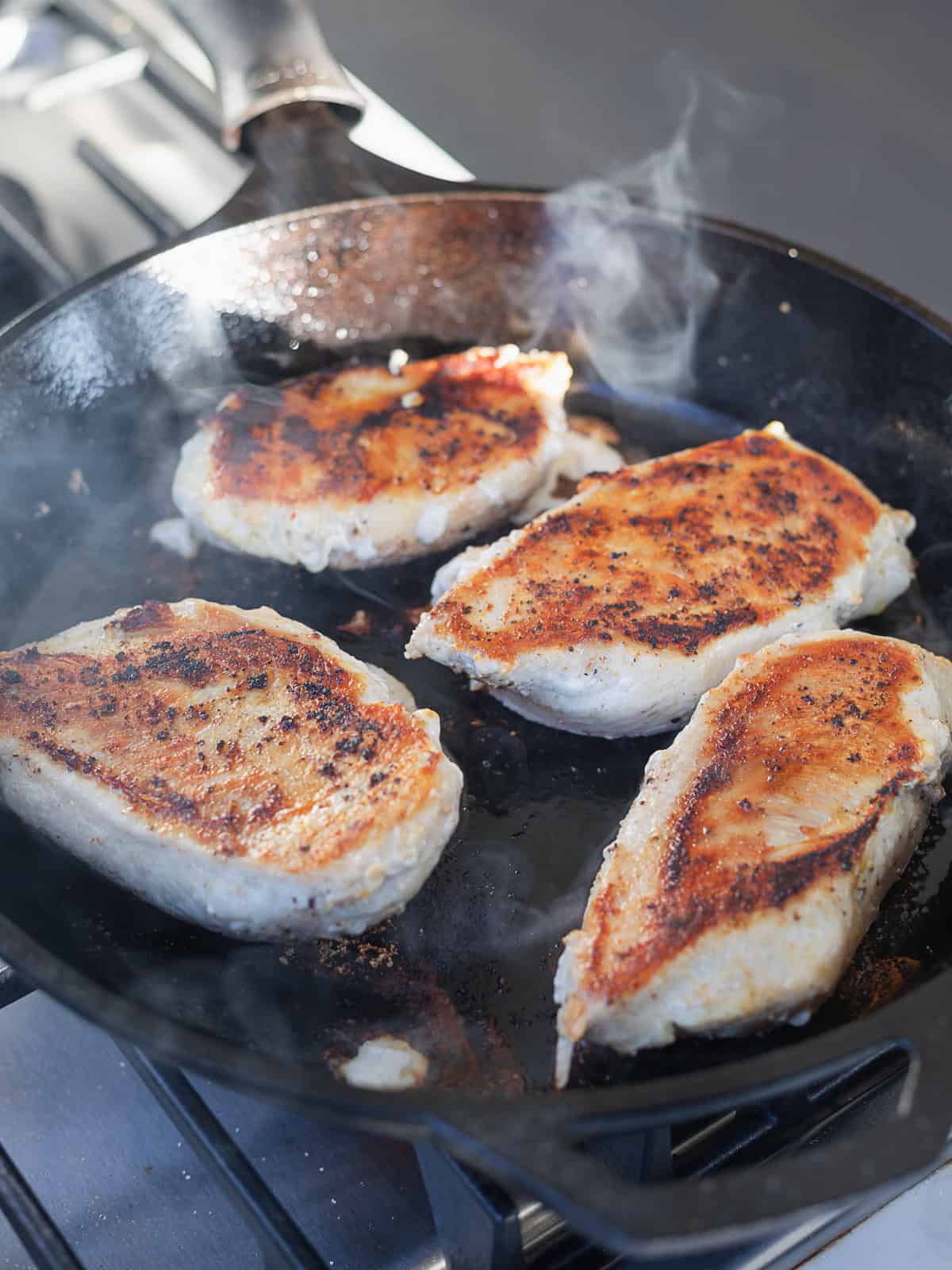 searing chicken breasts in a cast iron skillet