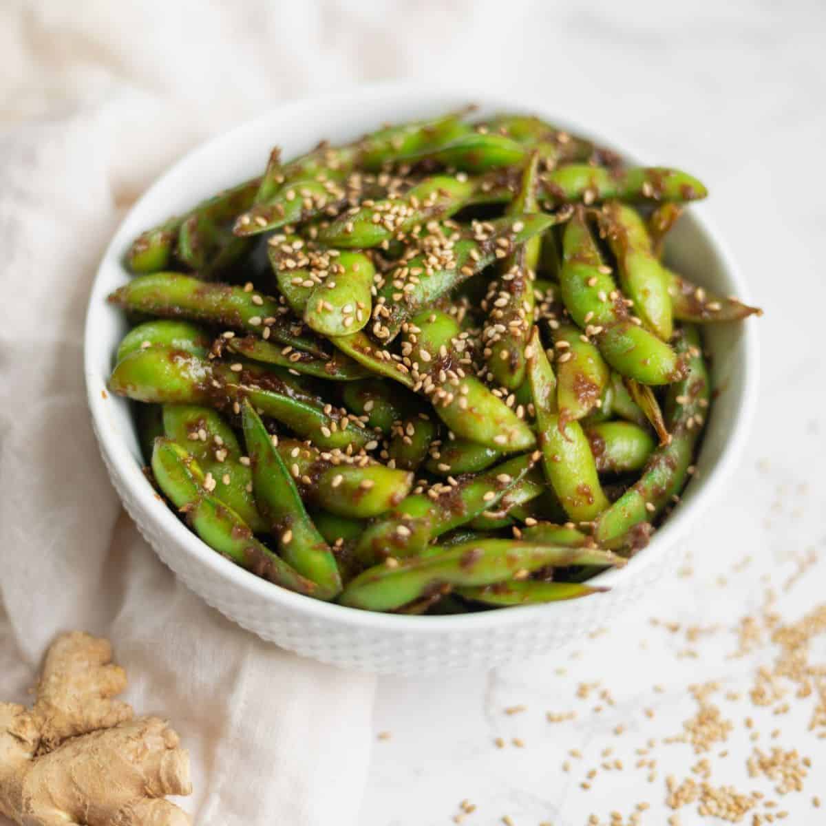 white bowl filled with edamame and topped with sesame seeds