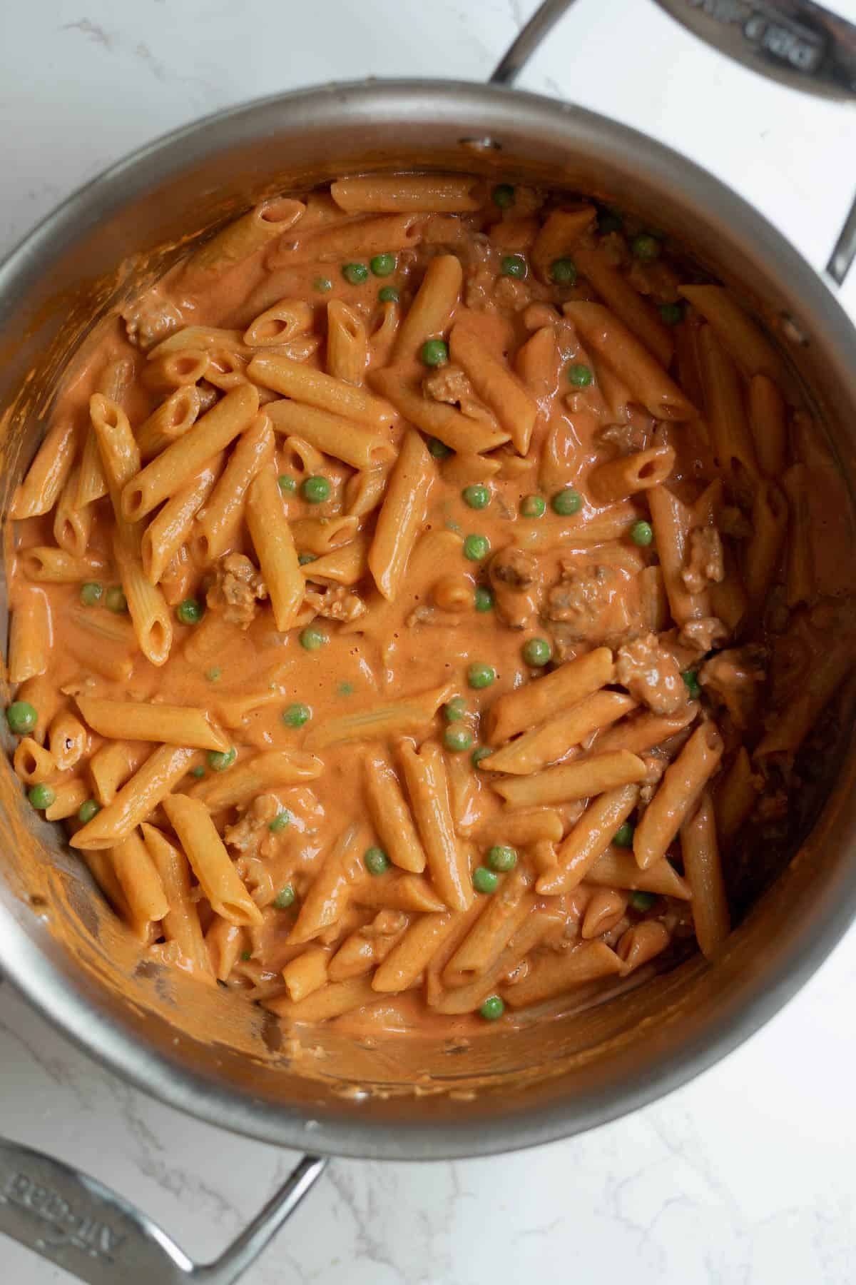 penne alla vodka with peas and pasta in a large silver pot