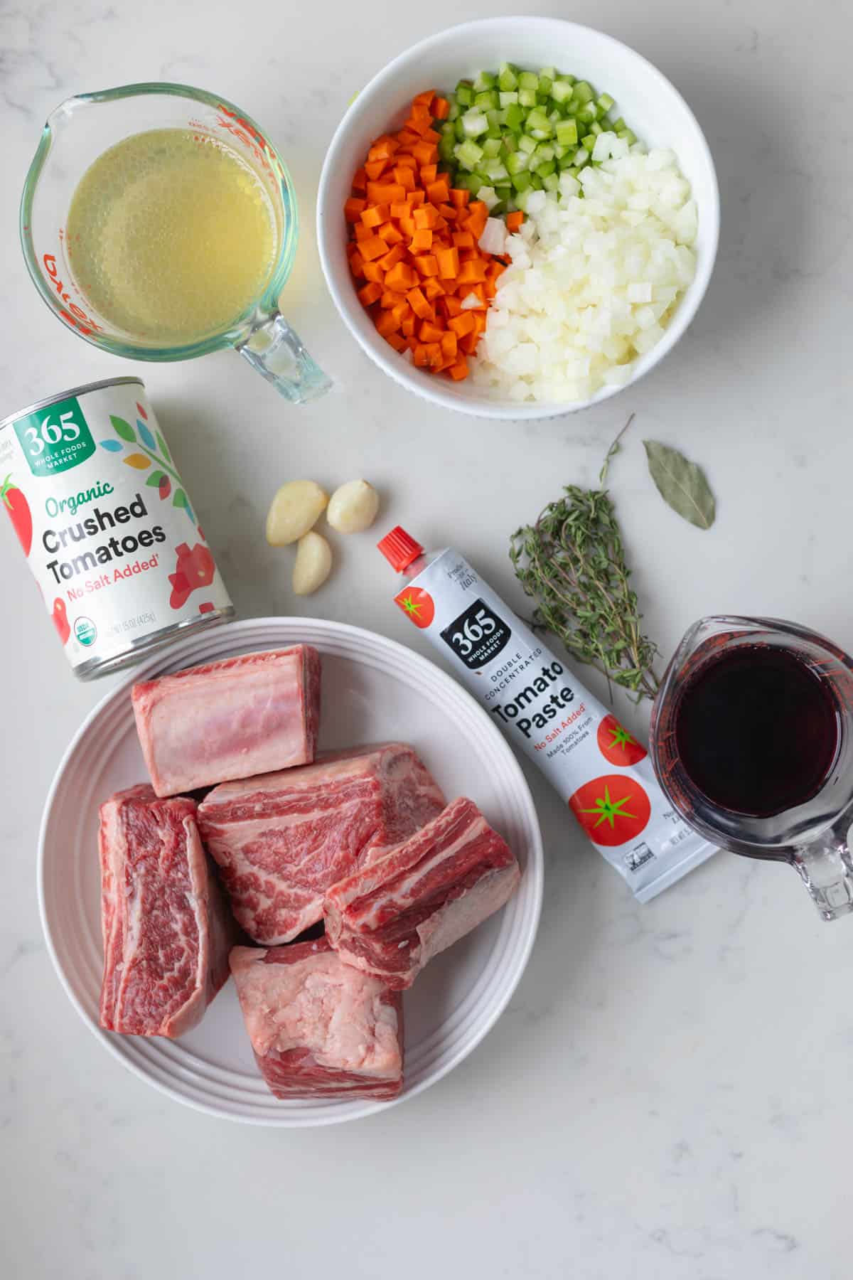 ingredients for ragu including short ribs, red wine, tomato sauce, thyme, tomato pasta, broth, and veggies