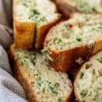 a close image of sliced cheesy garlic bread in a basket with a grey towel