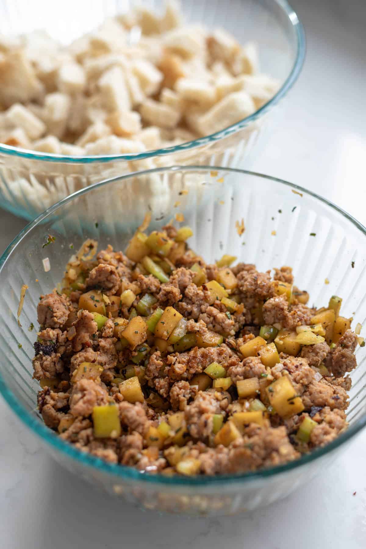 sausage in a clear bowl combined with cooked apples and celery
