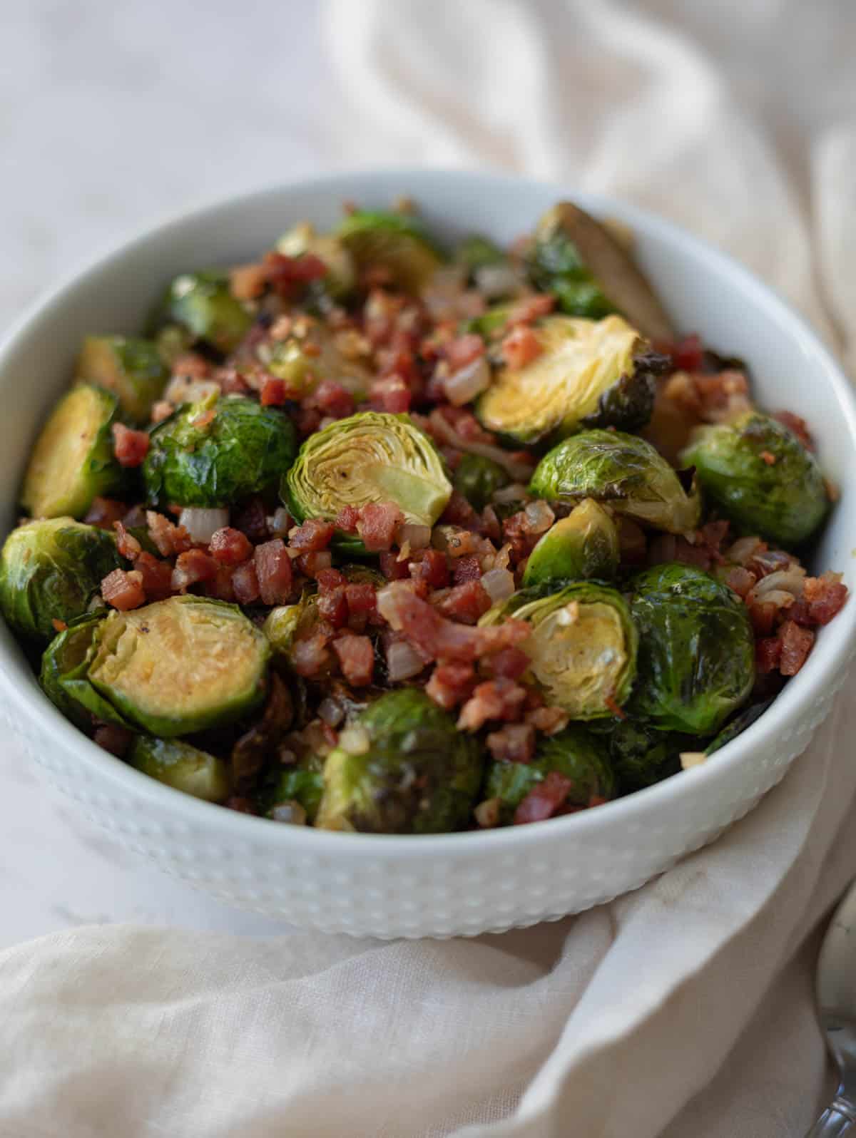 Brussel sprouts with pancetta in a white bowl