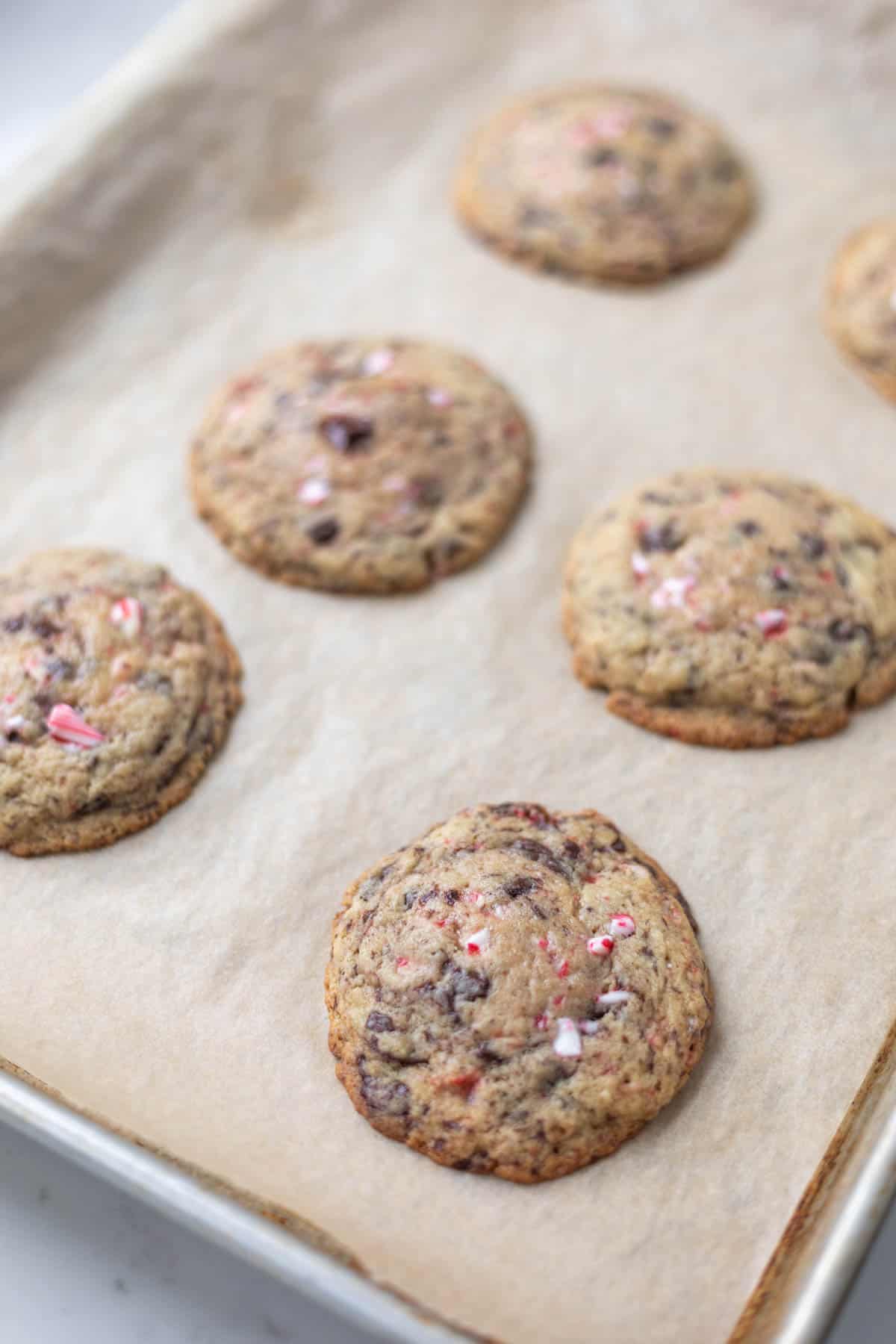 cooked peppermint chocolate chunk cookies on a baking sheet with brown parchment paper
