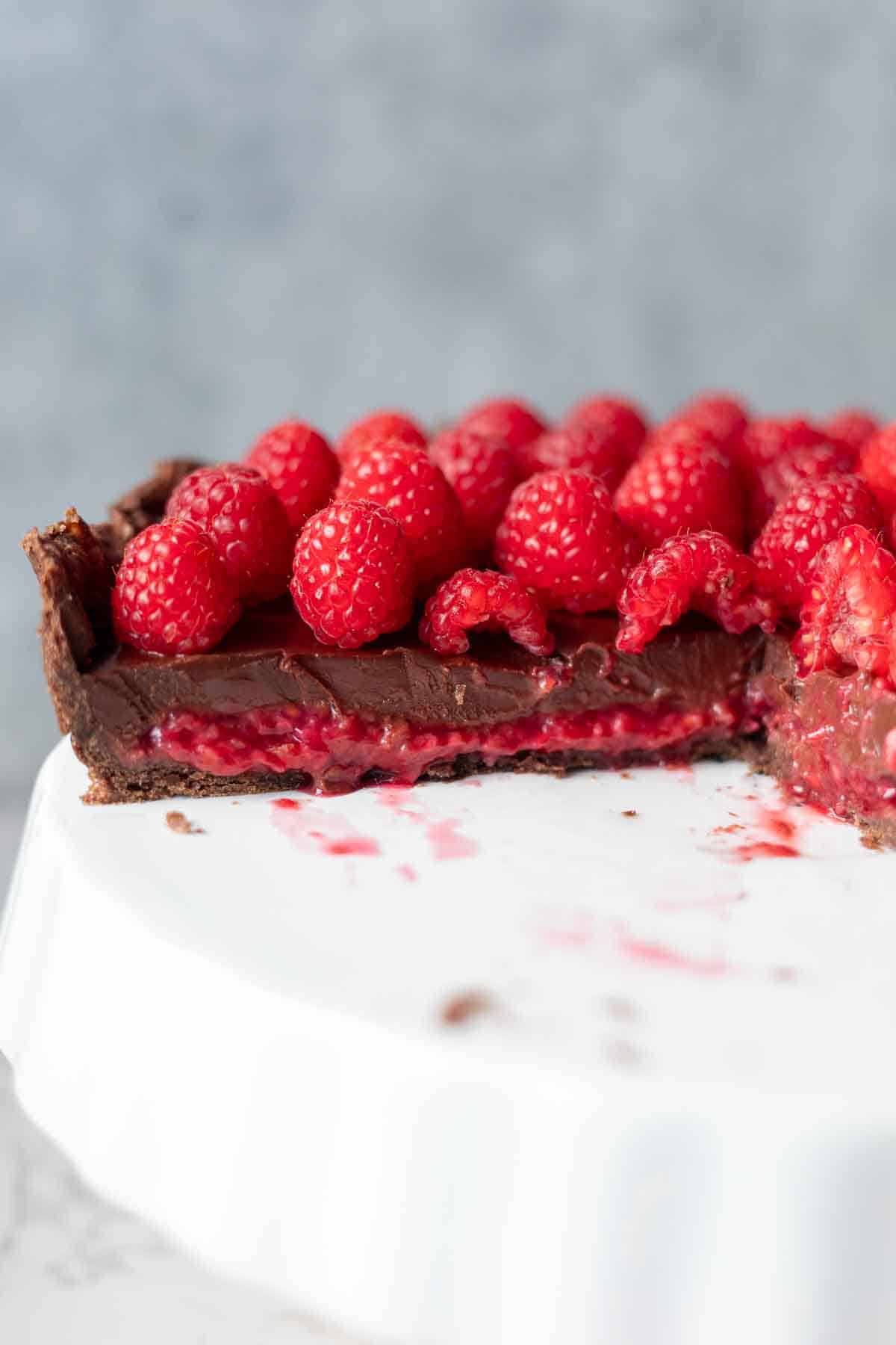 Close photo of raspberry and chocolate layered in the tart and topped with fresh raspberries.