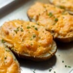 Cheesy loaded make ahead twice baked potatoes on a sheet pan topped with chives.